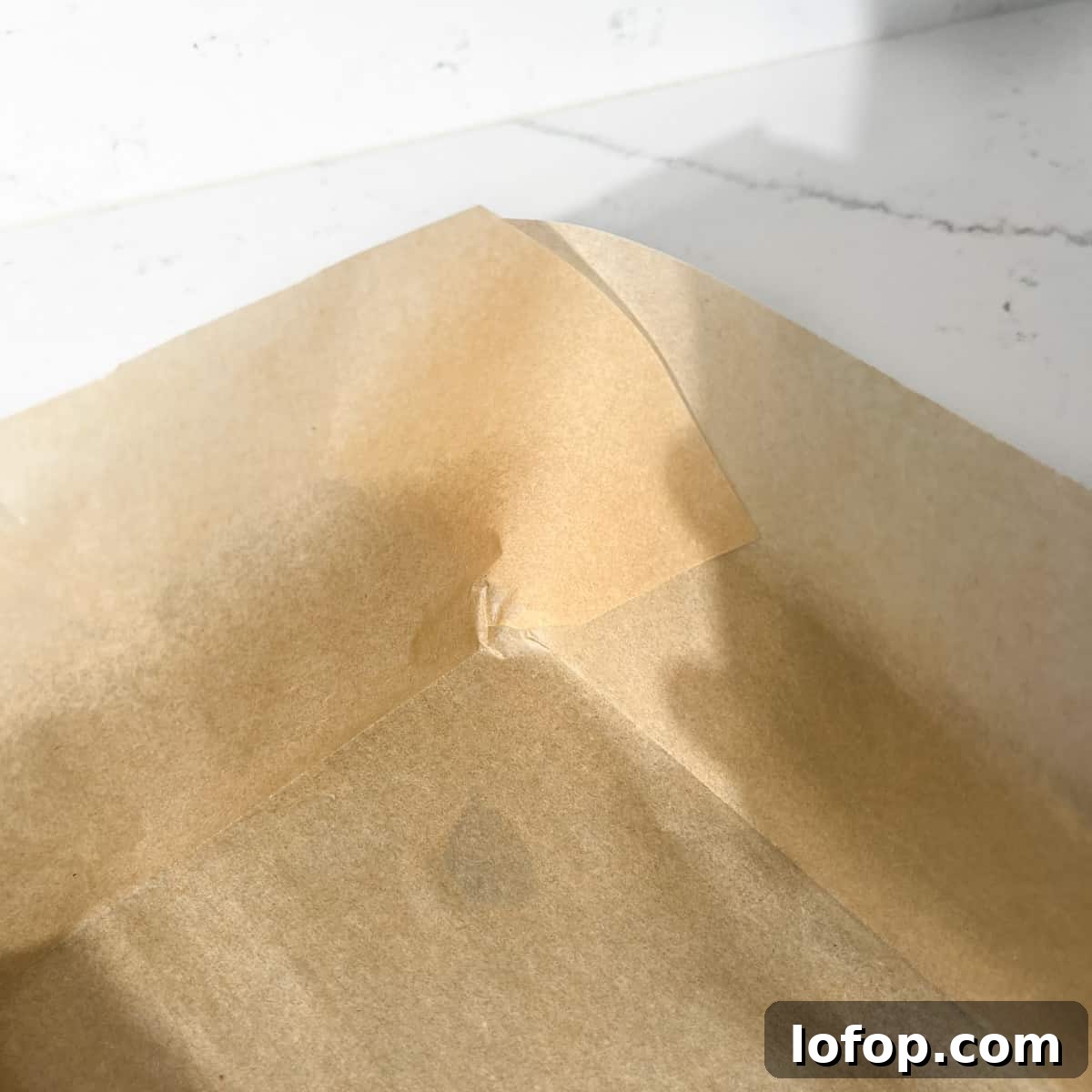 Overlapping corners of baking paper lining a baking tin.