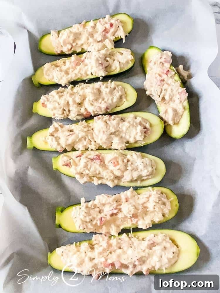 8 zucchini halves with seeds removed and topped with a chicken alfredo mixture on a baking sheet lined with parchment paper