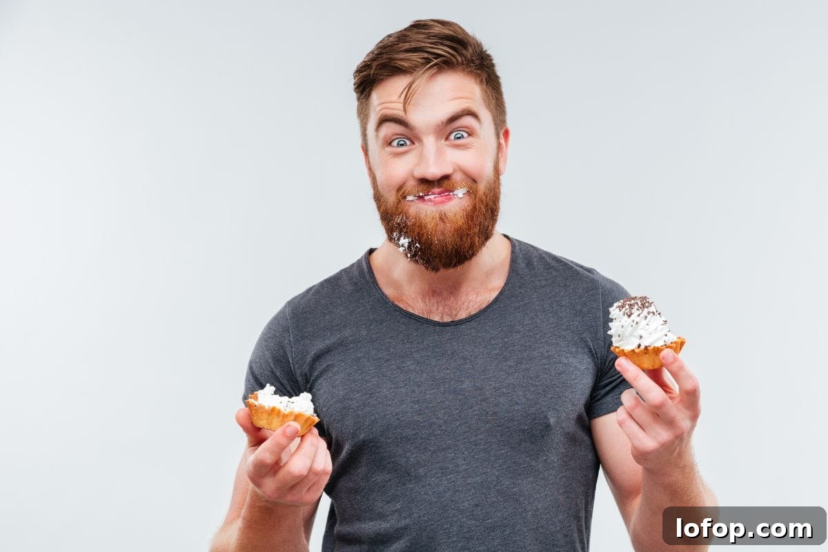 Man eating cupcakes with icing on his face 