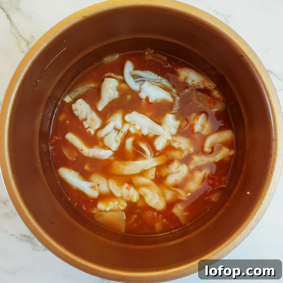 Octopus and stock added to onions in a pressure cooker.
