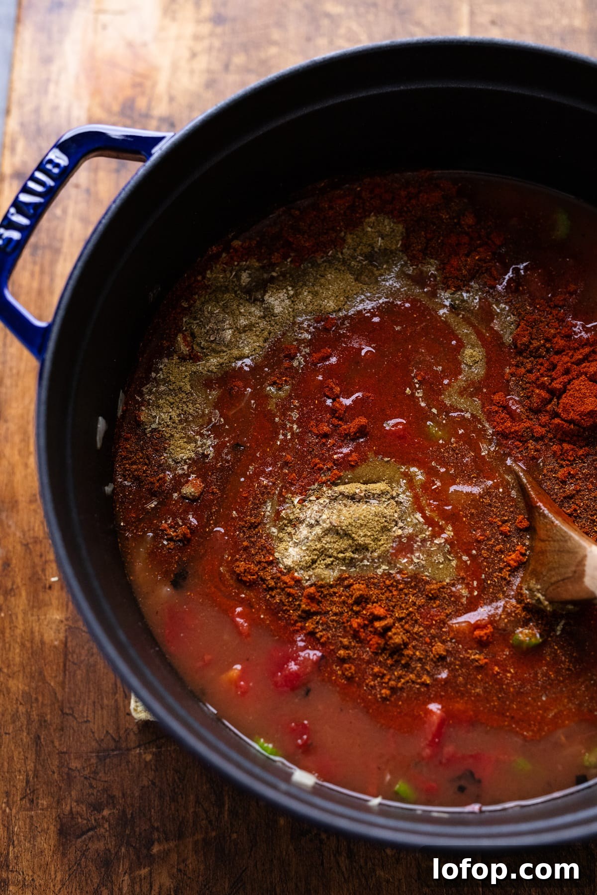 Hearty Vegetarian Black Bean Tortilla Soup Recipe 6 Spices being stirred into a pot with vegetarian tortilla soup in it.