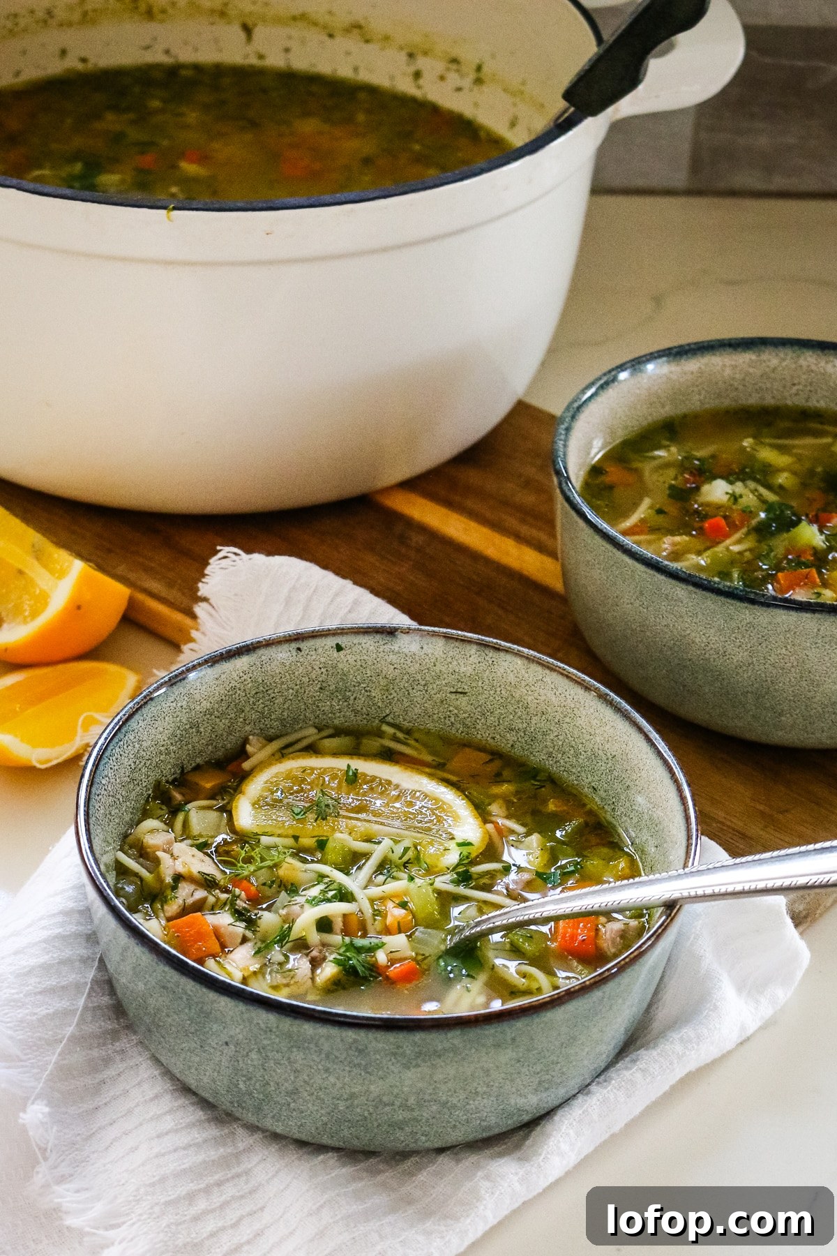 Romanian ciorbă soup served in a white pot and a white bowl.