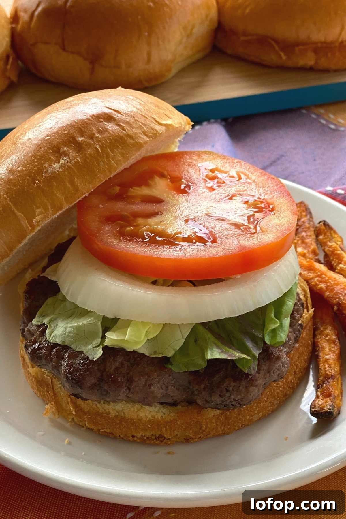 American Wagyu burger on a brioche bun topped with lettuce, onion and tomato.