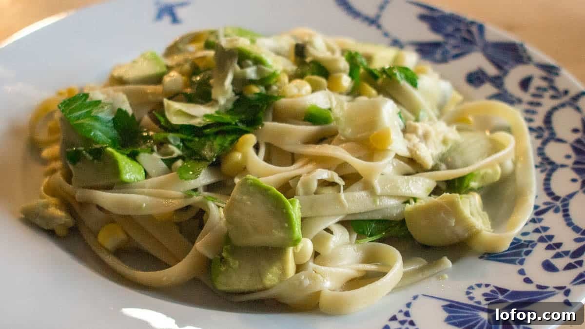 12 Flavor-Packed Meatless Dinners You’ll Love Tonight 13 A plate of fettuccine pasta topped with pieces of avocado, corn, and herbs on a patterned dish.