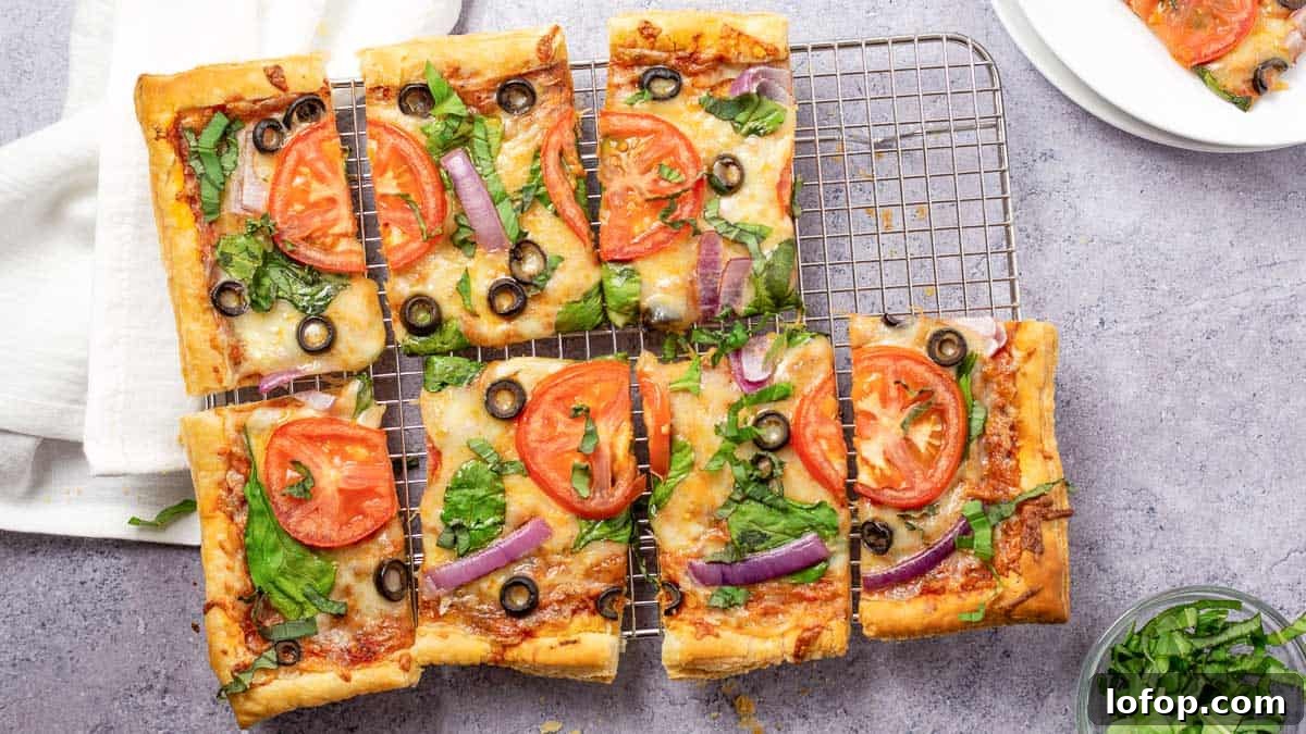 12 Flavor-Packed Meatless Dinners You’ll Love Tonight 6 Six rectangular vegetable pizzas with tomatoes, spinach, olives, and red onions on a cooling rack, with a white napkin nearby.