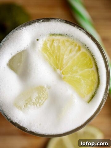 Brazilian lemonade server on a tall glass with lime slice and ice cubes.