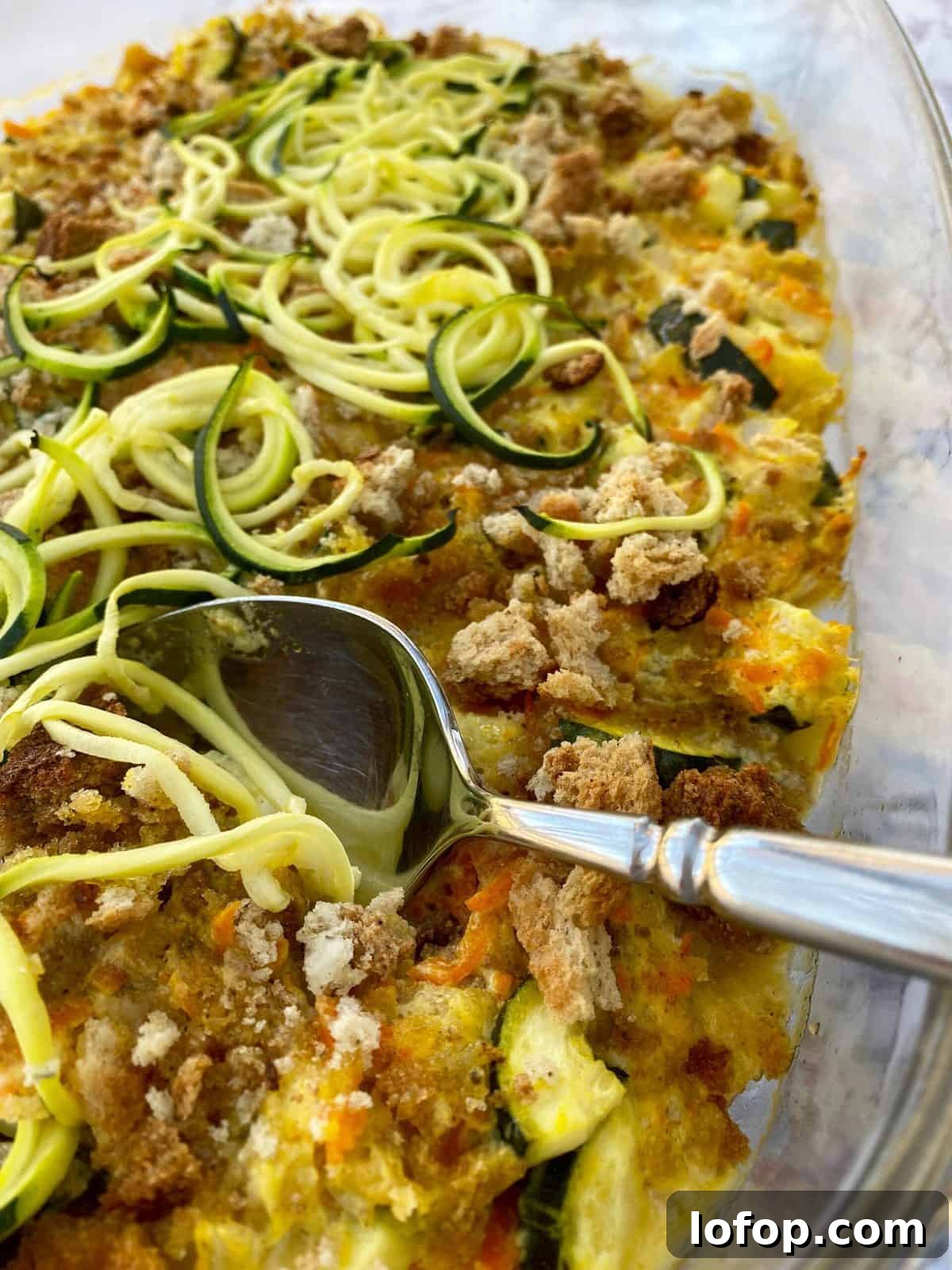 Zucchini and Herb Stuffing Casserole Recipe 7 Baking dish with zucchini casserole and a serving spoon.