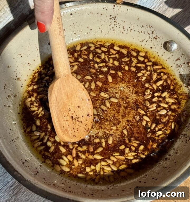 sunflower seeds in a saute pan with a wooden spoon in it