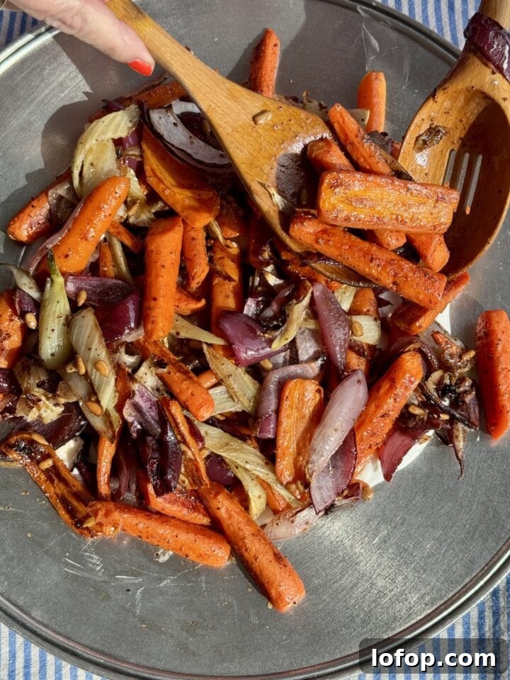 wooden spoons placing roasted vegetables on a silver platter