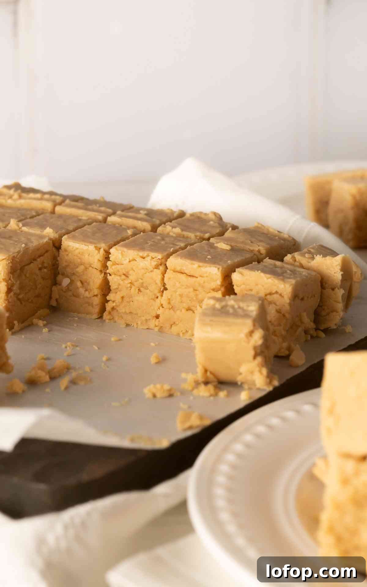 Creamy Peanut Butter Fudge Recipe for Rich Homemade Candy 4 Side view of cut peanut butter fudge on a wooden board.