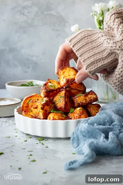 Someone taking a roast potato from a white dish next to a napkin