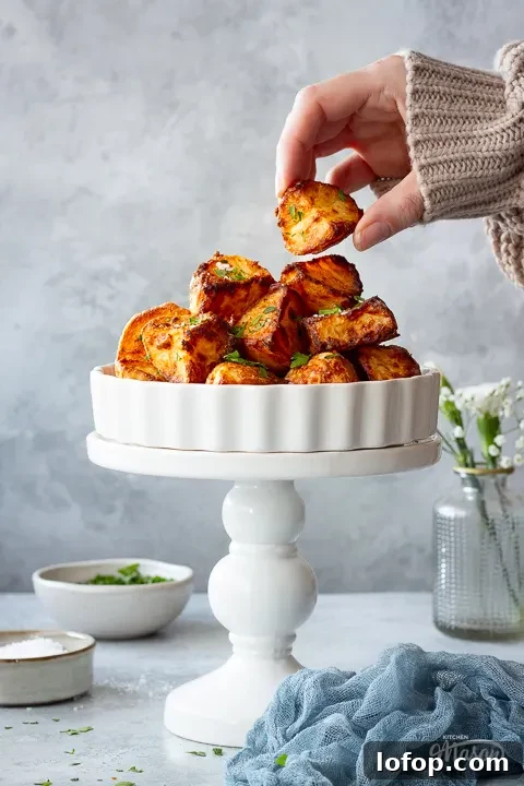 Someone taking an air fryer roast potato from a dish
