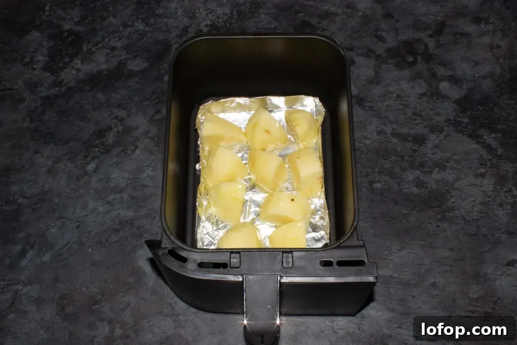 potatoes in a tin foil tray in an air fryer drawer