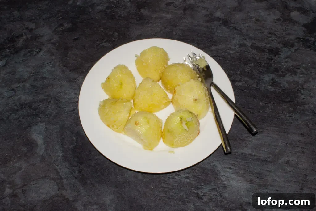 Part cooked potatoes being fluffed up with a fork