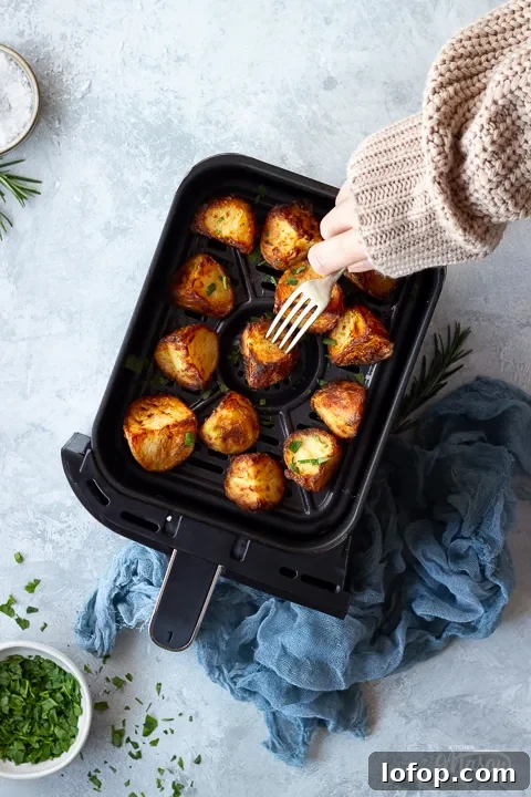Someone forking an air fryer roast potato in an air fryer drawer