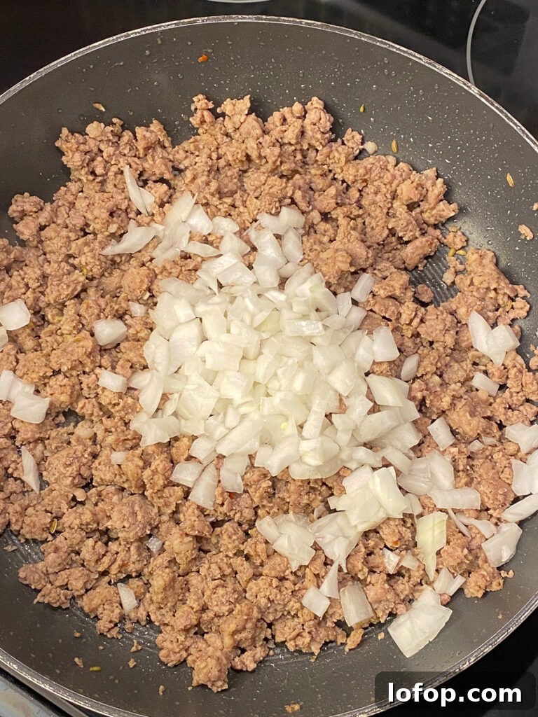 Creamy Pizza-Stuffed Bell Peppers Recipe for Weeknight Dinner 5 Browned ground beef and Italian sausage in a skillet with chopped onions on top