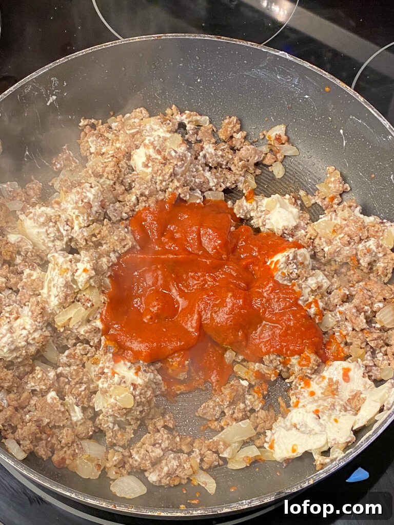 Creamy Pizza-Stuffed Bell Peppers Recipe for Weeknight Dinner 6 Cream cheese and pizza sauce added to a skillet with crumbled and browned meat