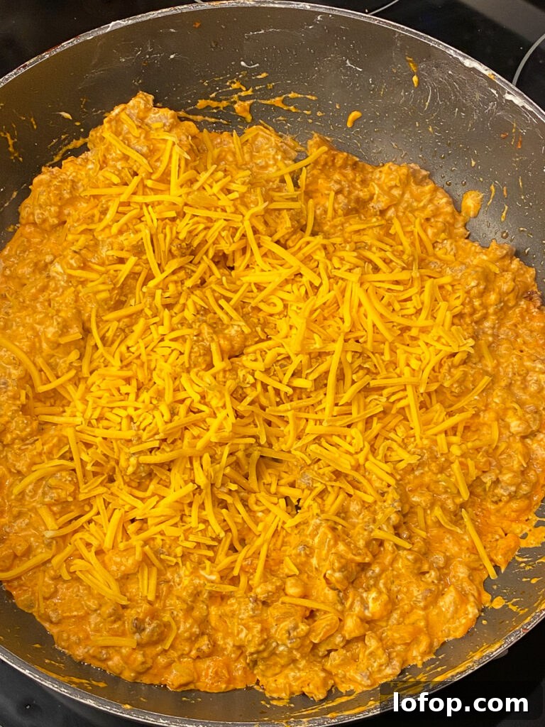 Creamy Pizza-Stuffed Bell Peppers Recipe for Weeknight Dinner 7 Shredded cheddar cheese on creamy meaty mixture in a large skillet