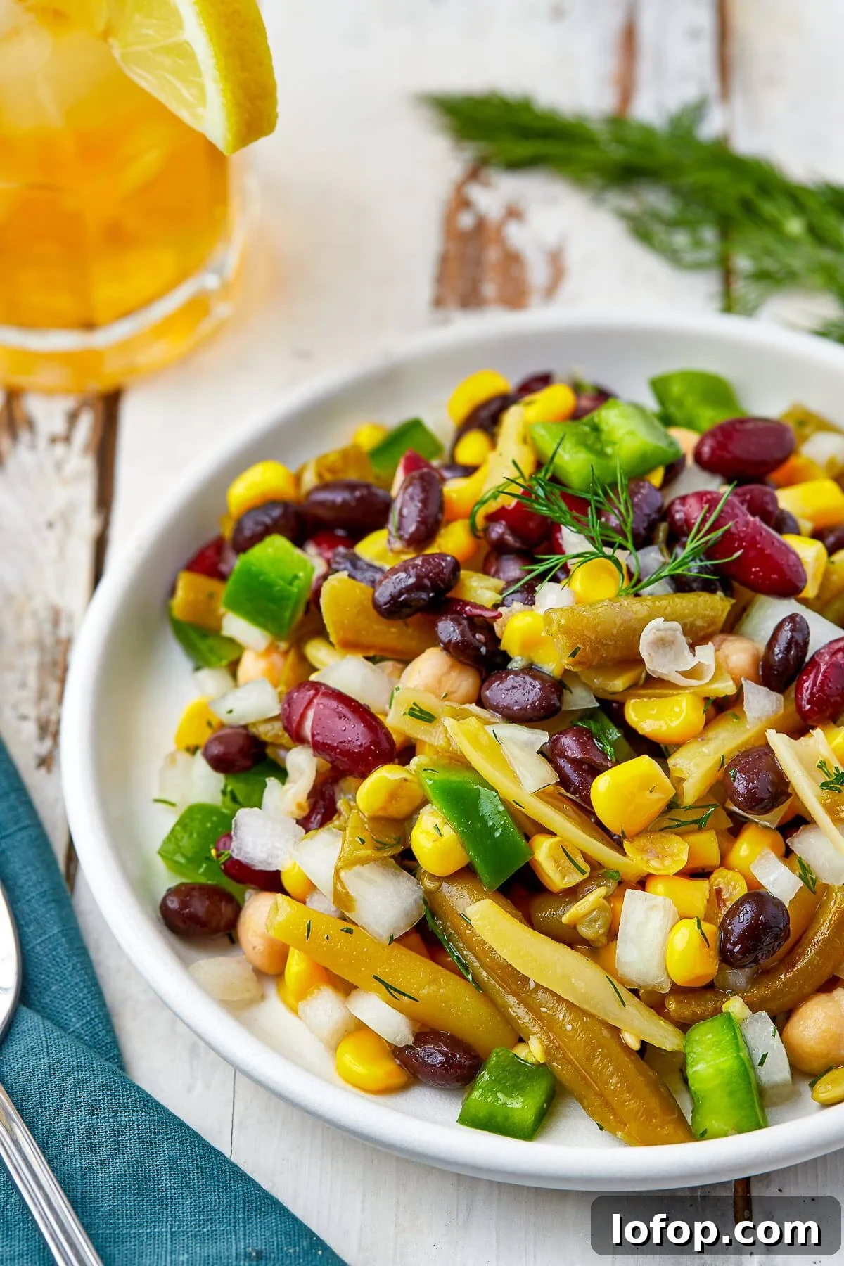 Creamy Vinaigrette Five-Bean Salad Recipe 8 A bowl of bean salad served with fresh dill and a cold drink.