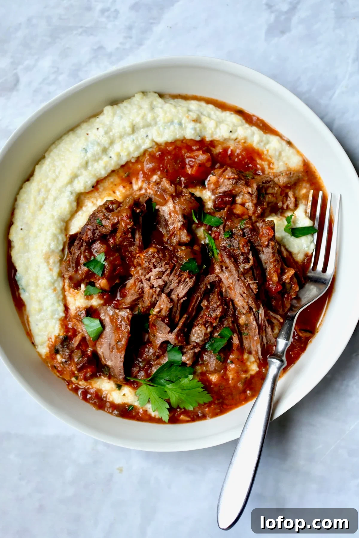 Authentic Stracotto: Italian Pot Roast Recipe for Slow-Cooked Beef 9 One serving of Italian Pot Roast (Stracotto) in white dinner bowl with fork.
