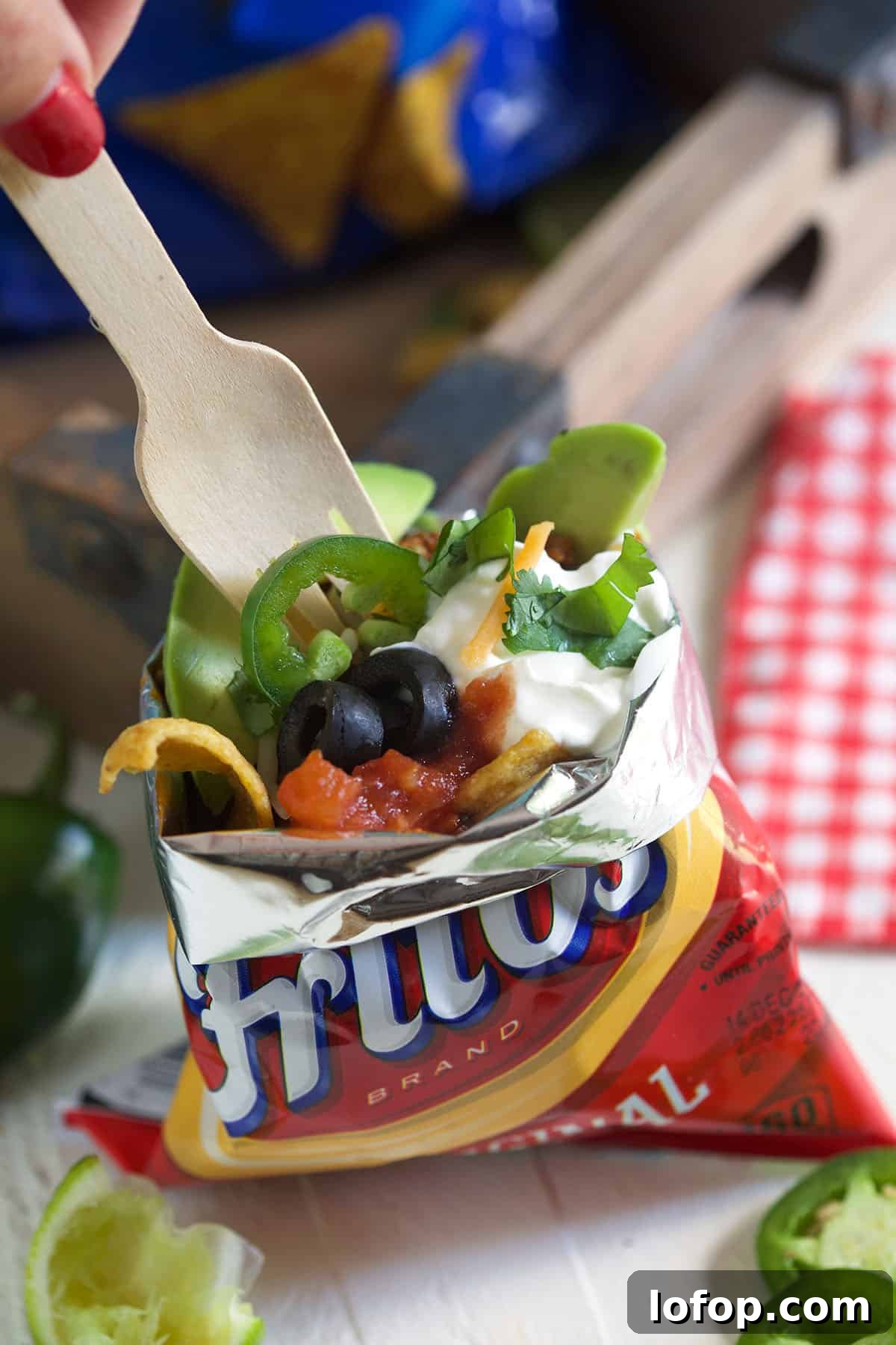 Walking Tacos: Easy Portable Taco Cups for Parties and Picnics 3 A fork is digging into a bag of frito's that's filled with all sorts of taco ingredinets.