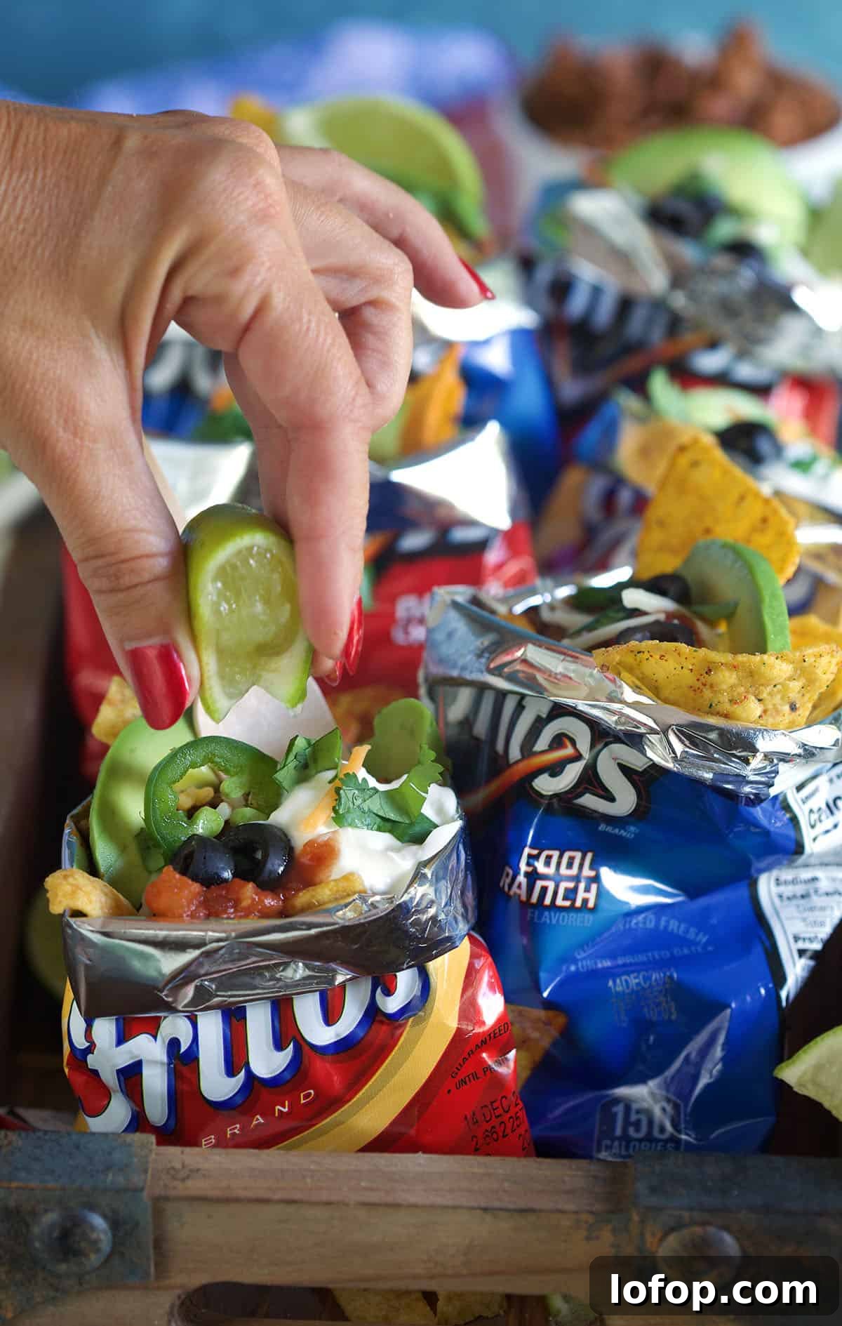 Walking Tacos: Easy Portable Taco Cups for Parties and Picnics 4 A lime is being squeezed into a bag of wlaking tacos.