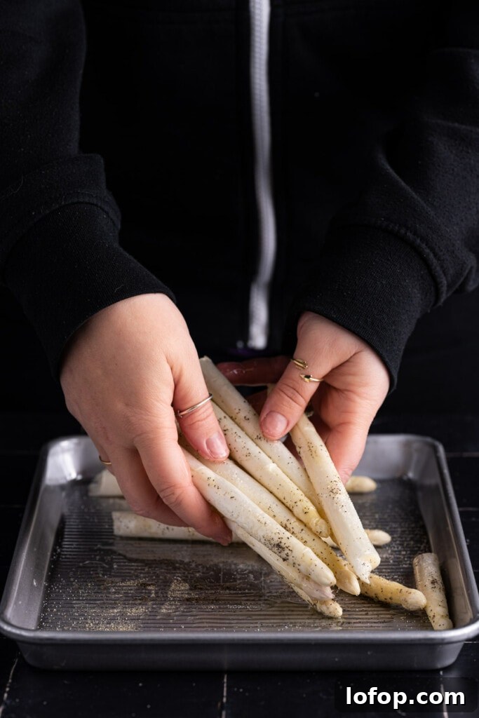Tossing white asparagus in salt pepper and olive oil.