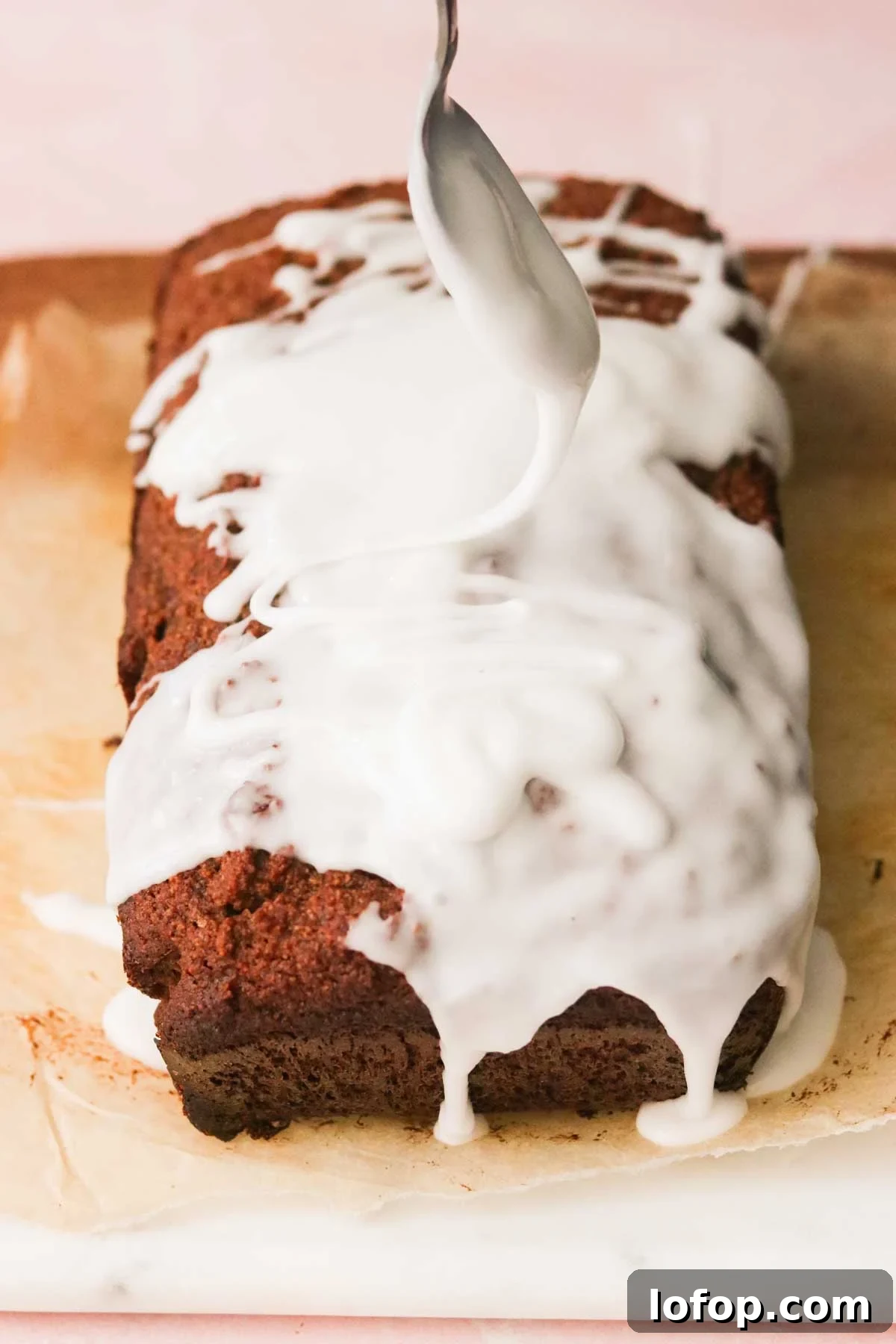 a silver spoon drizzling sugar glaze on top of a gluten free gingerbread loaf