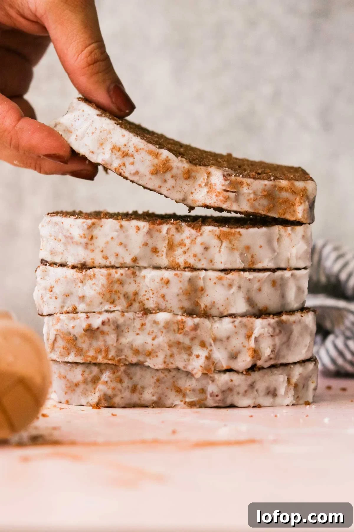 a hand stacking slices of sugar glazed gingerbread slices