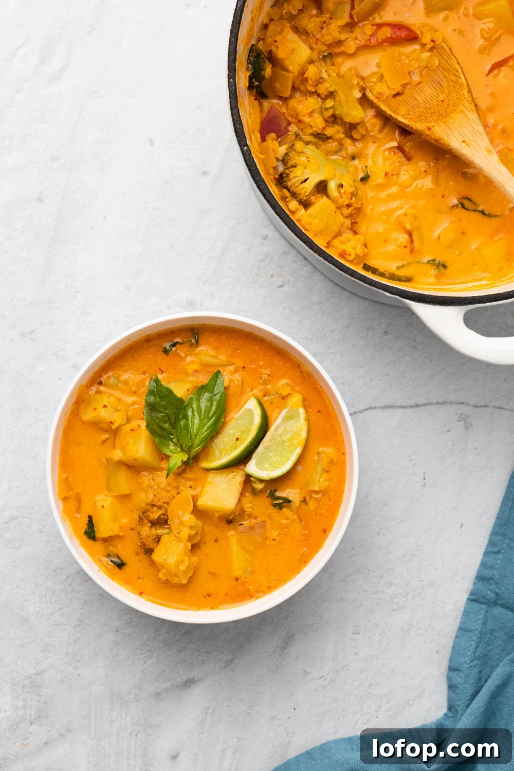 a bowl of vegan Thai sweet potato curry with red lentils next to a pot