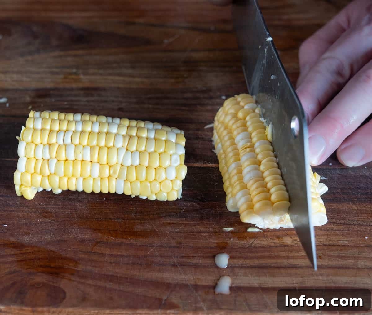 Cutting corn halves into quarters on a cutting board.