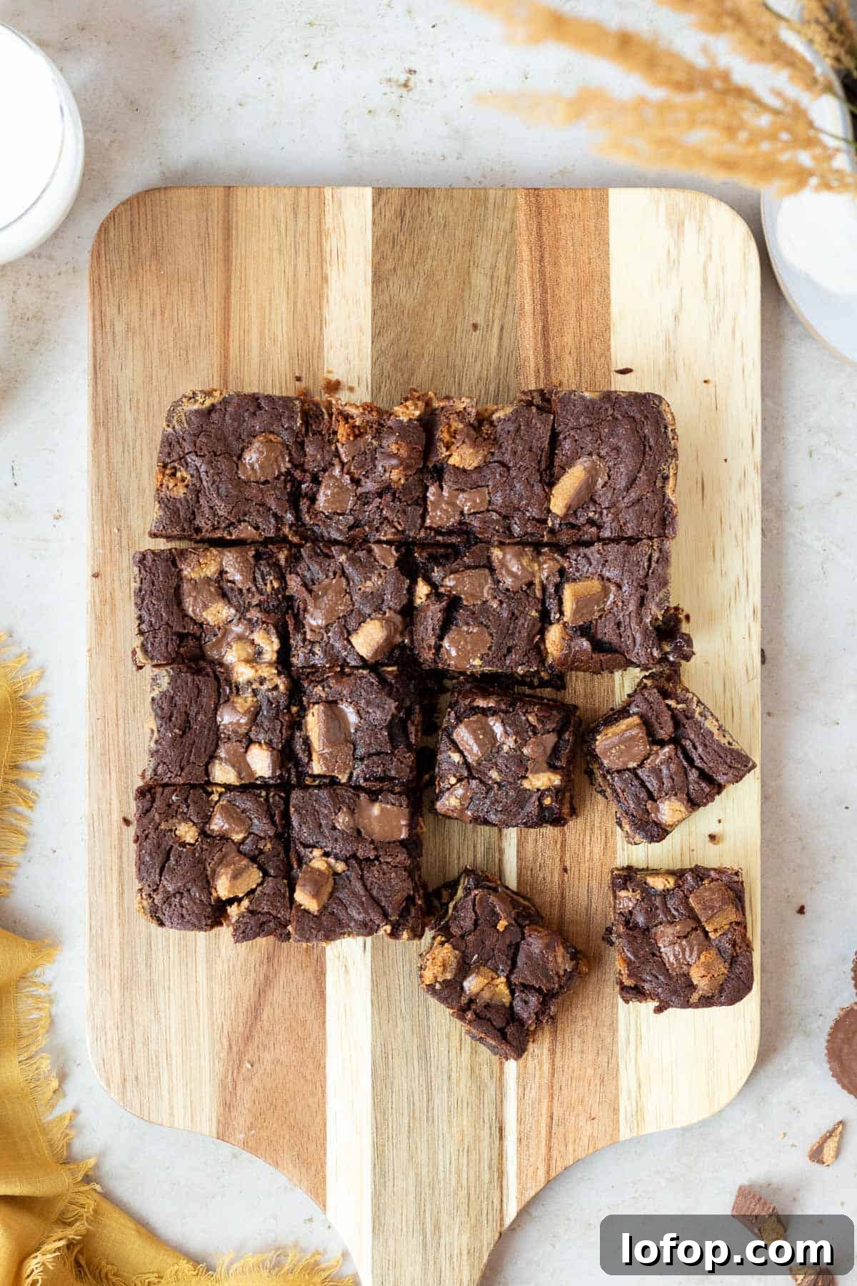 Decadent Peanut Butter Cup Fudgy Brownies Recipe 3 slab of peanut butter cup brownies cut into squares sitting on top of a wooden cutting board