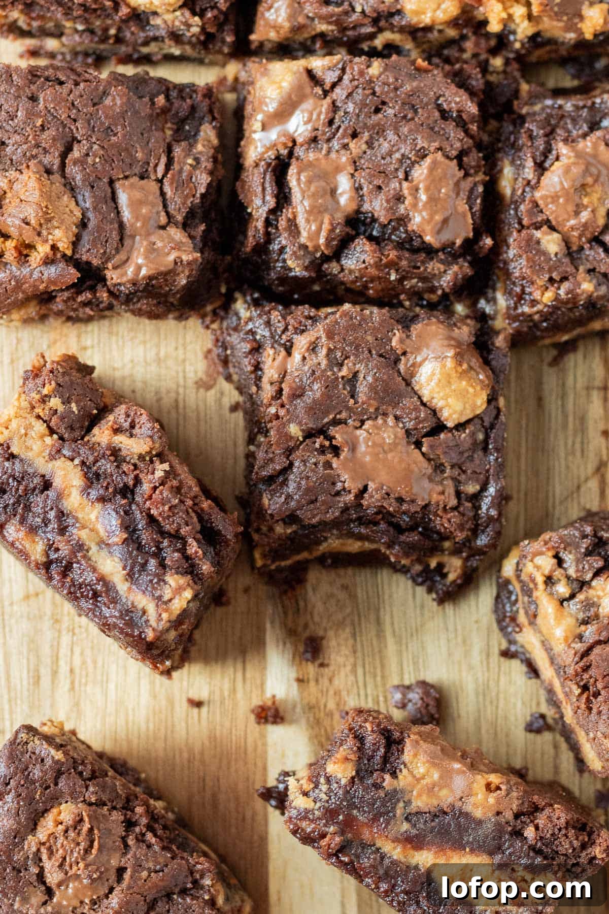 Decadent Peanut Butter Cup Fudgy Brownies Recipe 6 peanut butter cup brownies on a cutting board with some on their side showing a layer of peanut butter filling