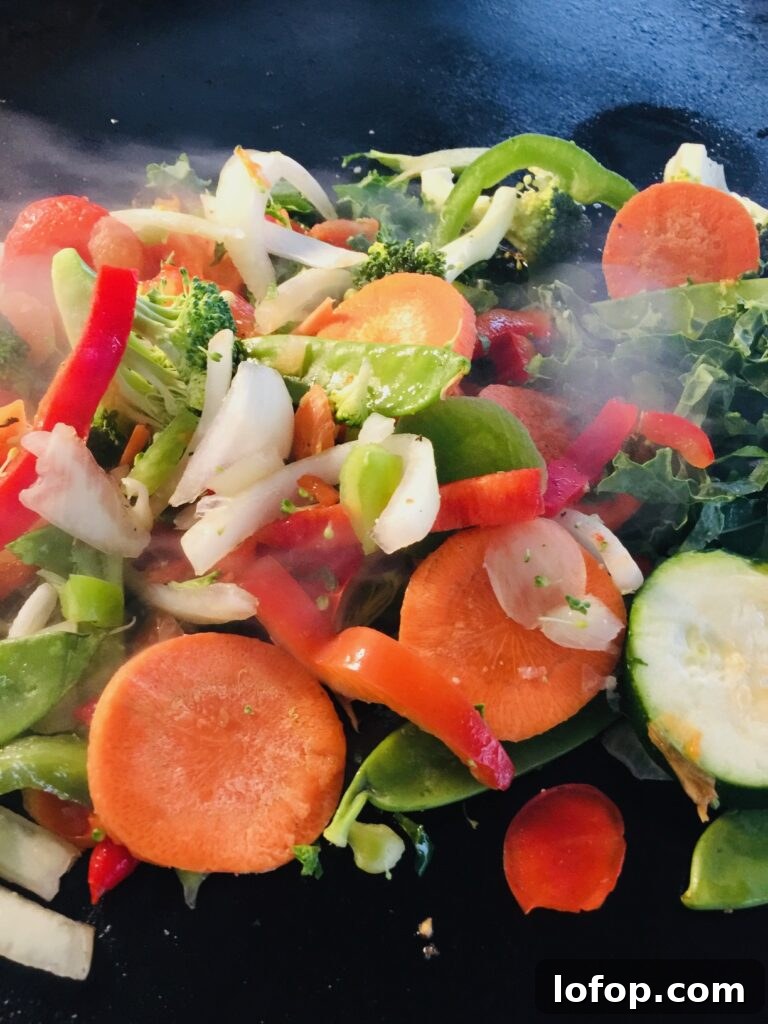adding the vegetables for Blackstone Peanut Chicken Stir Fry