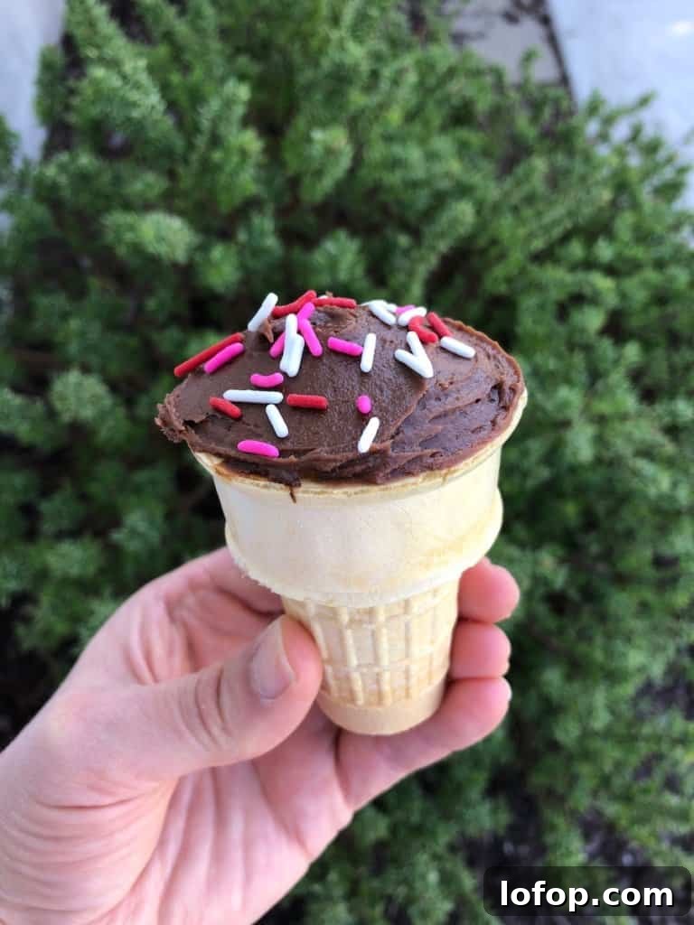 Classic Ice Cream Cone Cake Recipe from Childhood Favorites 2 A hand holding an ice cream cone cupcake.