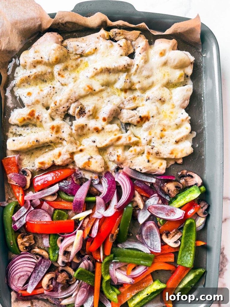Sheet pan with veggies and cheesy chicken morsels.