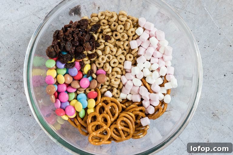 ingredients to make sweet and salty snack mix - marshmallows, pretzels, cheerios, m&Ms and raisins