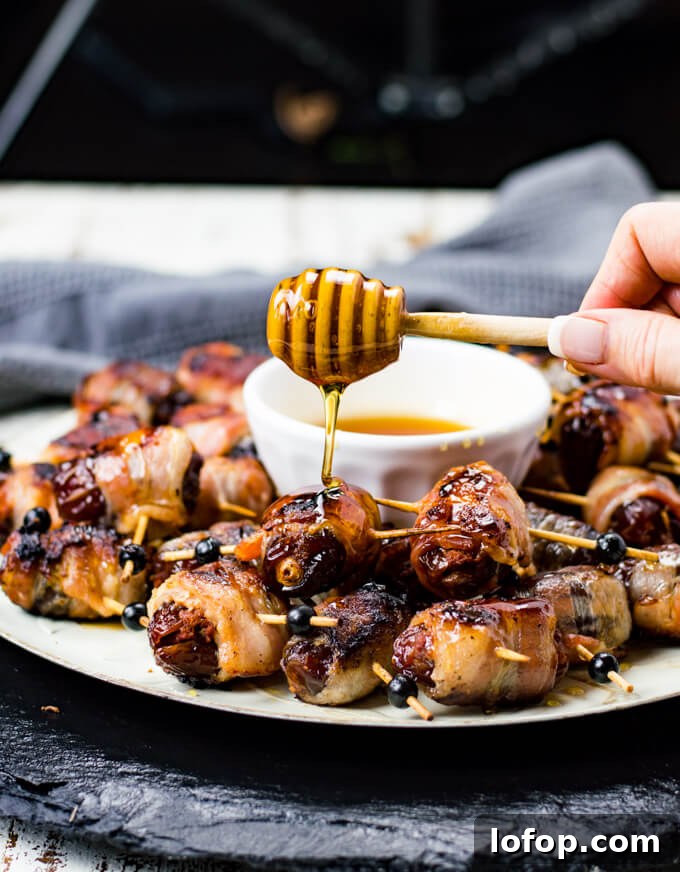 Bacon-Wrapped Stuffed Dates with Goat Cheese and Almonds 7 A platter of bacon wrapped dates with honey drizzling over them.