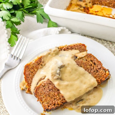 Savory Mushroom Meatloaf with Rich Mushroom Gravy 12 2 slices of mushroom meatloaf with gravy served on a white plate