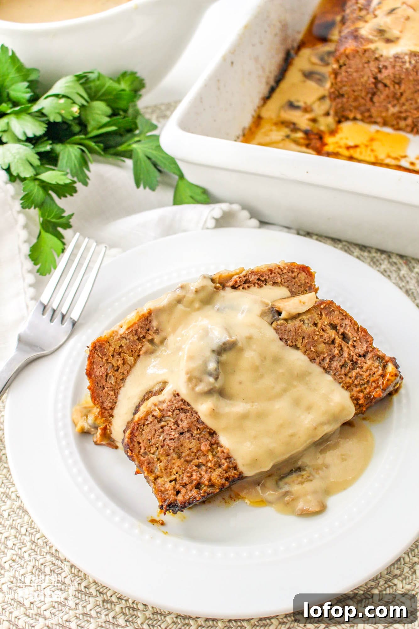 Savory Mushroom Meatloaf with Rich Mushroom Gravy 10 2 slices of mushroom meatloaf served on a white plate, with creamy mushroom gravy on top