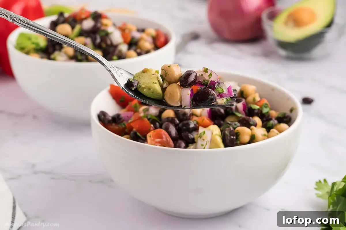 A forkful with black bean and chickpea salad on it.