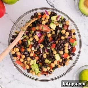 An overhead view of a glass bowl with black bean and chickpea salad.