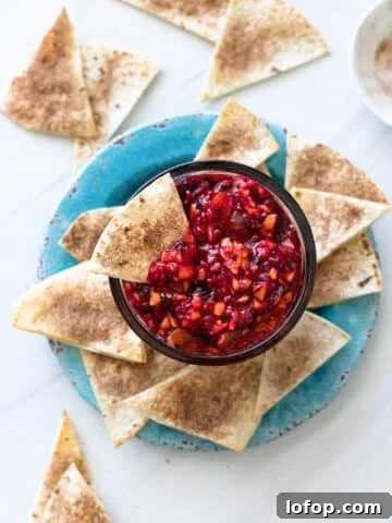 Bowl filled with fruit salsa and cinnamon chips being served alongside.