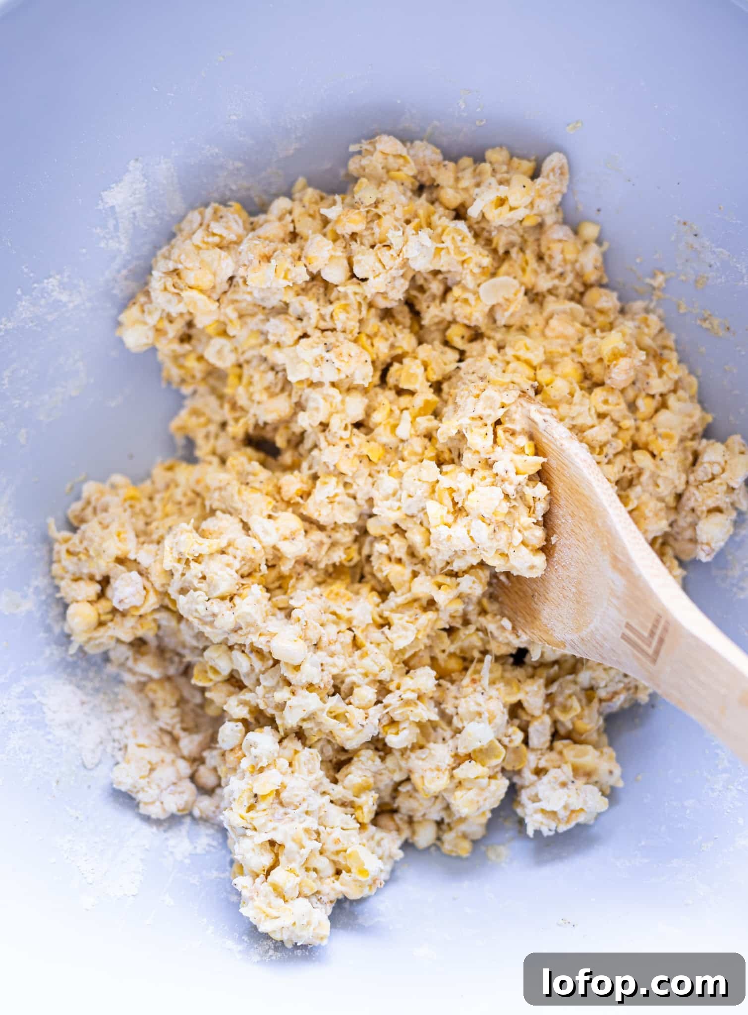 Corn and flour being stirred in a bowl. 