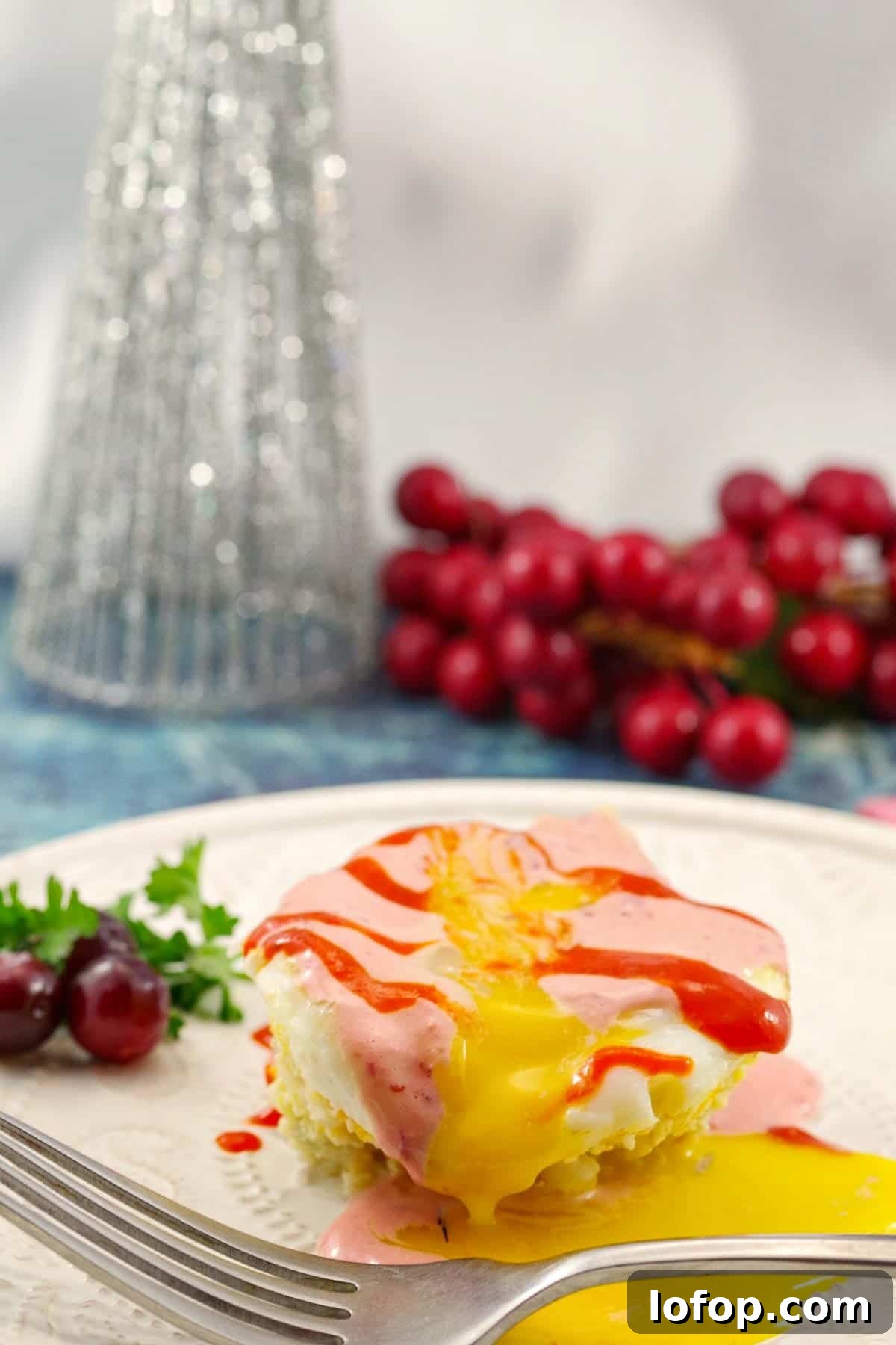 Ham and Rice Muffin-Tin Eggs Benedict with Cranberry Hollandaise 3 muffin tin eggs benedict on a white plate with cranberries and a Christmas tree decoration in the background