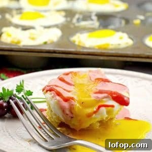 muffin tin eggs benedict on white plate with more muffin tin eggs benedict in muffin tin in background