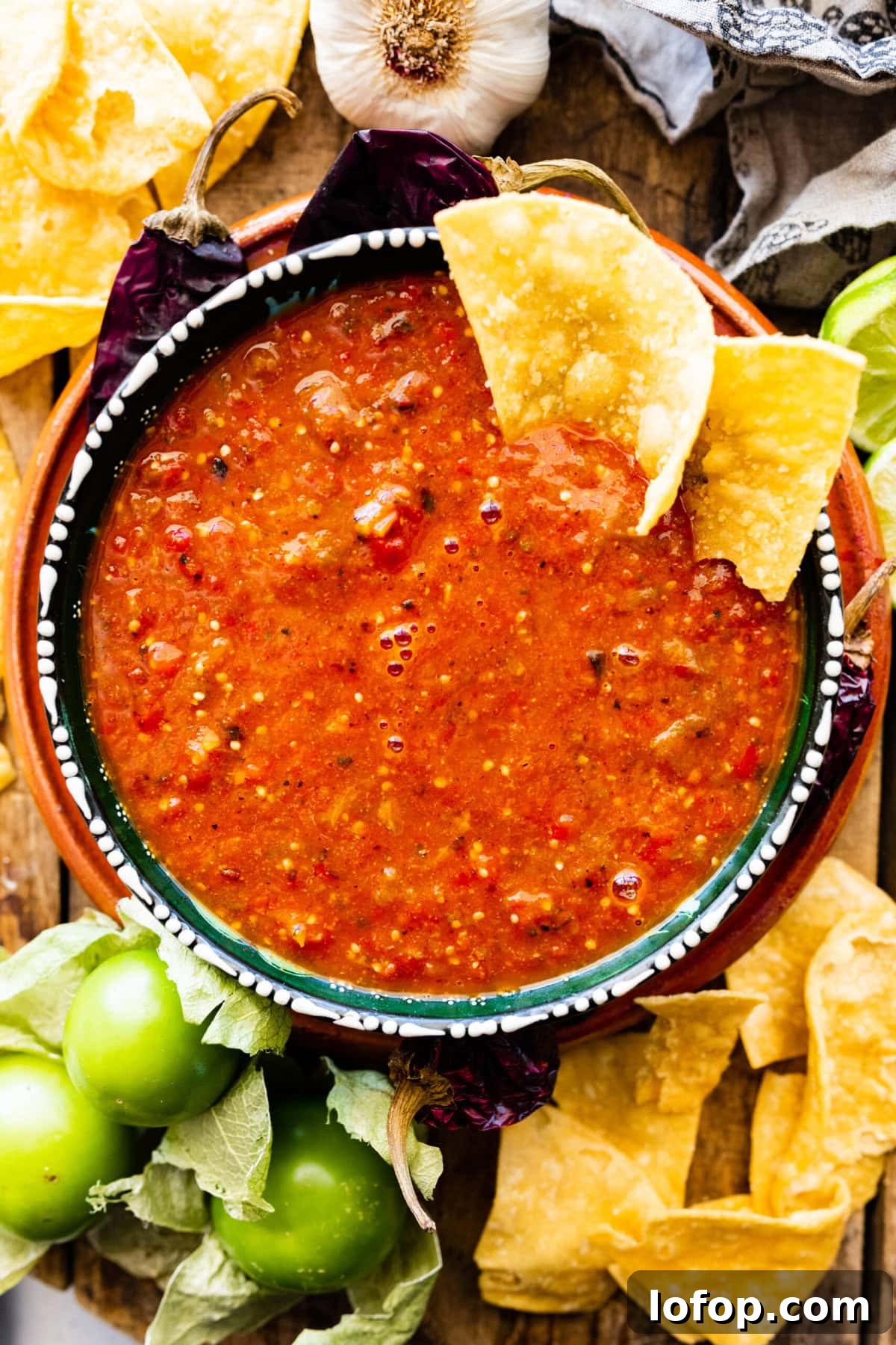 Copycat Chipotle Red Chili Salsa Recipe: Authentic Hot Salsa 2 Chipotle Hot Salsa Recipe (Copycat) in a Mexican-style bowl with limes, chips, and dried chiles.