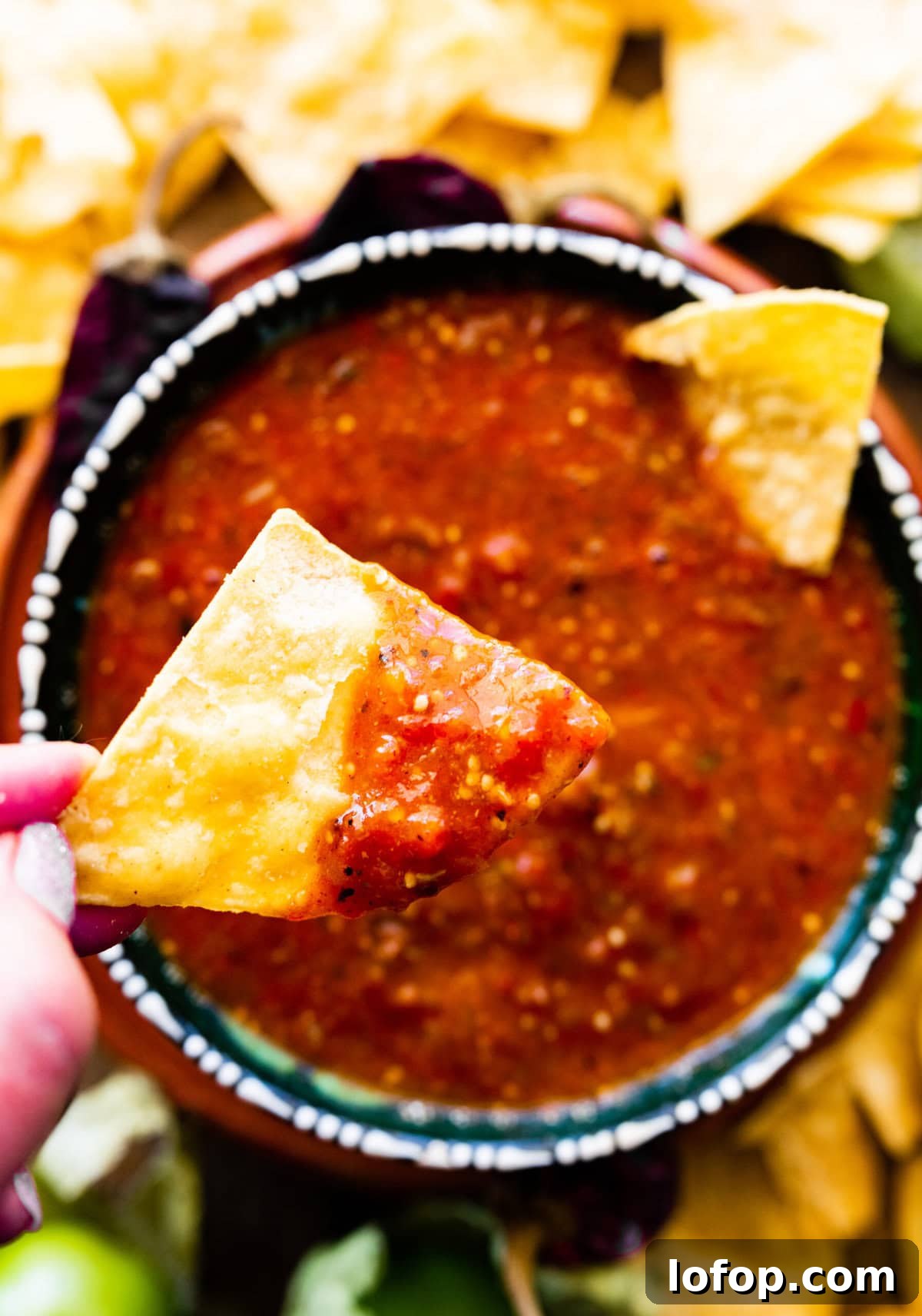 Copycat Chipotle Red Chili Salsa Recipe: Authentic Hot Salsa 11 Hand holding a chip dipped in copycat Chipotle hot salsa.