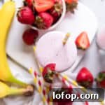 a smoothie with strawberries and bananas on a white plate.