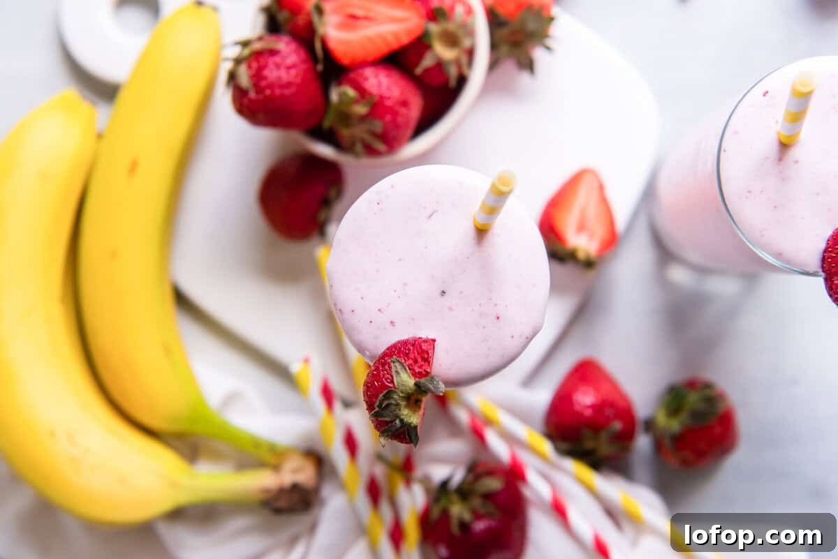 a smoothie with strawberries and bananas on a white plate.